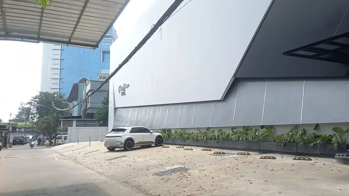 The white facade of Glass House Padel with its script logo